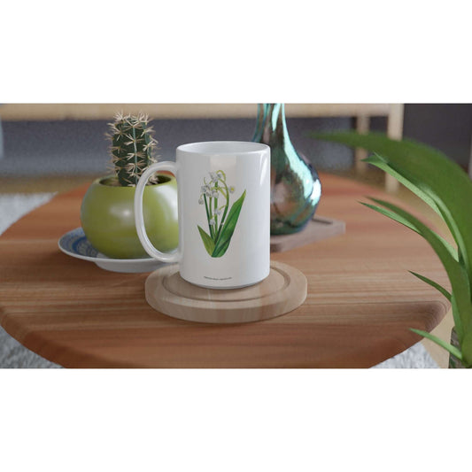 Lily of the Valley Flower Mug 15oz on a wooden coaster next to a plant and a decorative plate