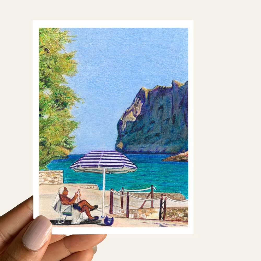 Close up of greeting card of a man sitting by the beach under an umbrella reading the newspaper
