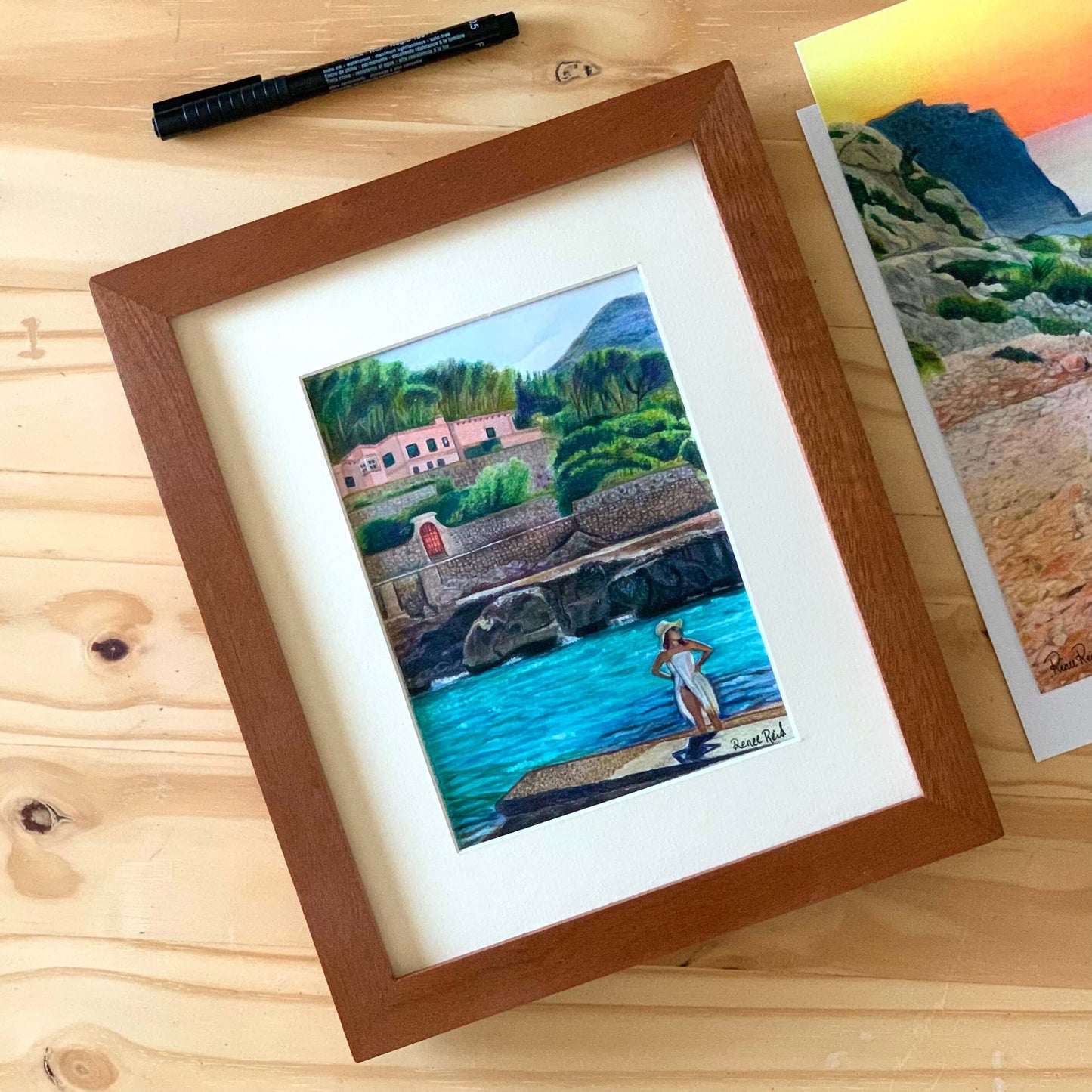 Renee Reid framed original artwork of a woman on a beachside landing glazing into the distance