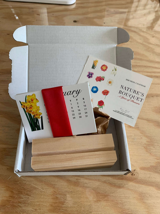 2026 Floral Mini Desk Calendar displayed in an open box with floral cards and a wooden holder.