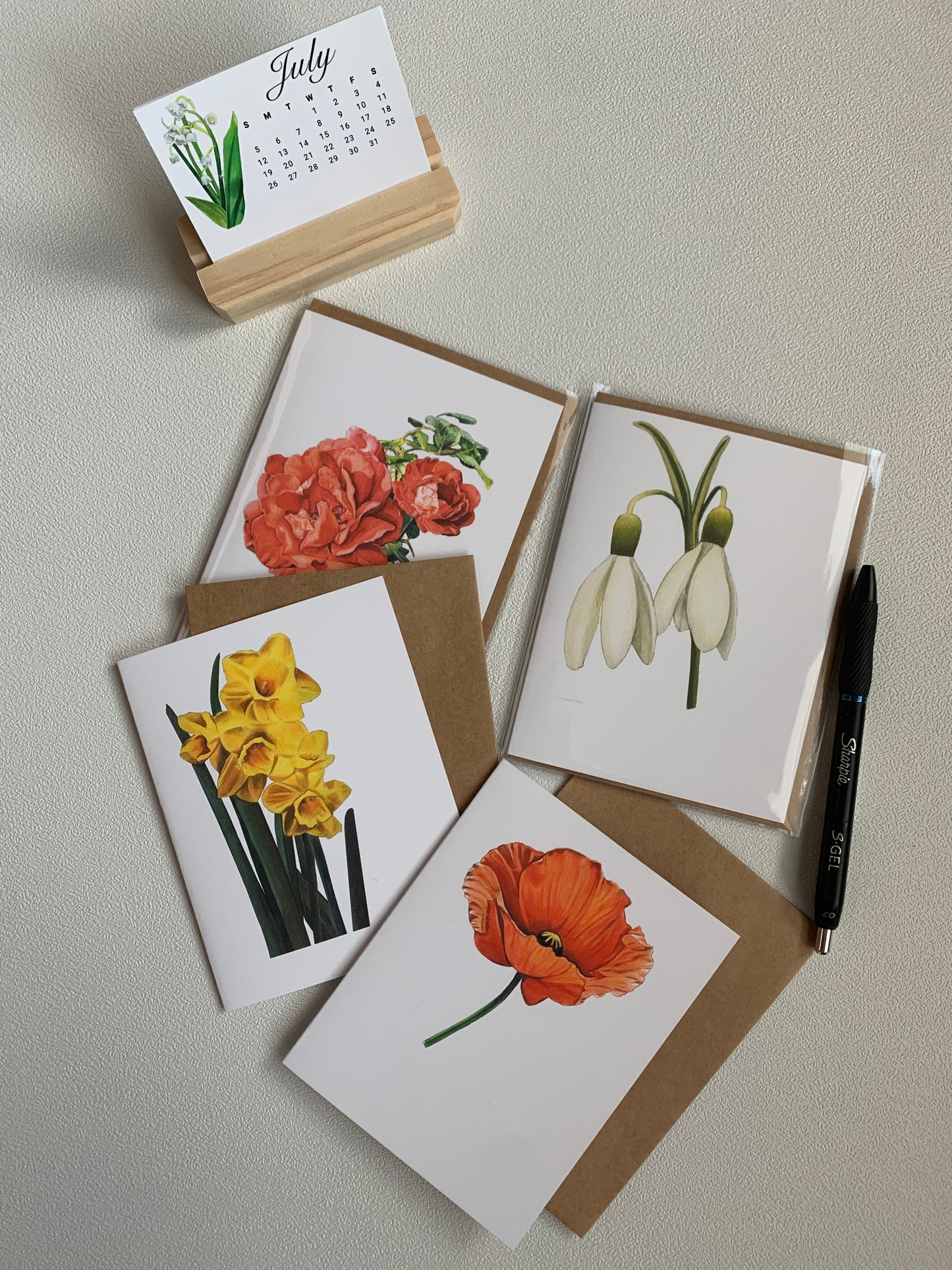 Floral Greeting Card Boxed Set featuring illustrated floral designs with a calendar and pen on a table.