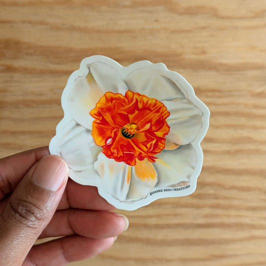 Hand holding a Orange Narcissus Flower Vinyl Sticker design on a wooden surface