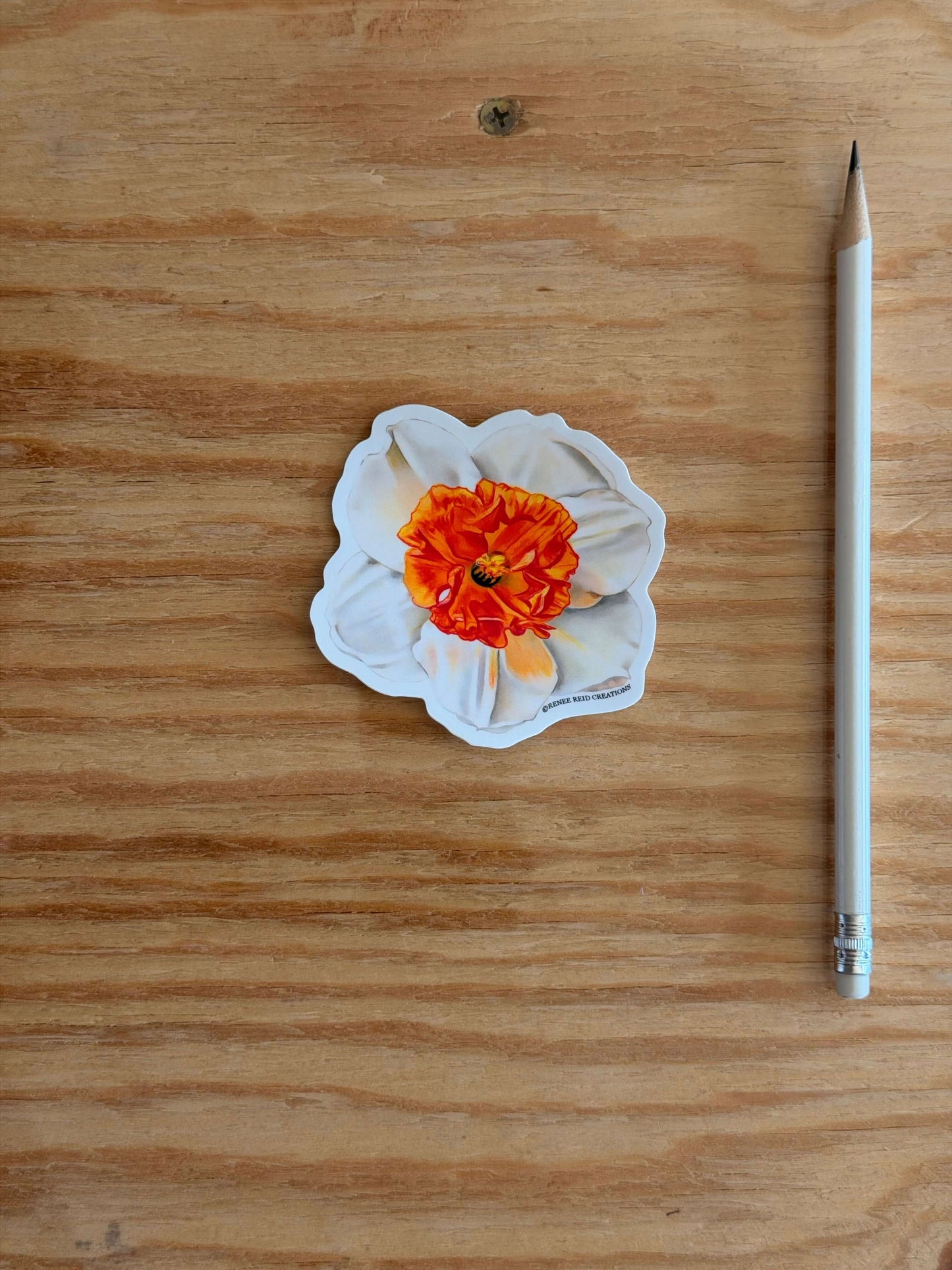 Orange Narcissus Flower Vinyl Sticker on a wooden surface next to a pencil