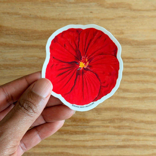 Hand holding a Red Hibiscus Flower Sticker on a wooden surface