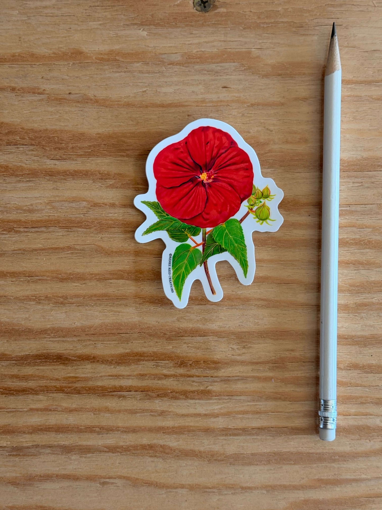 Red Hibiscus Flower Sticker on a wooden surface with a pencil