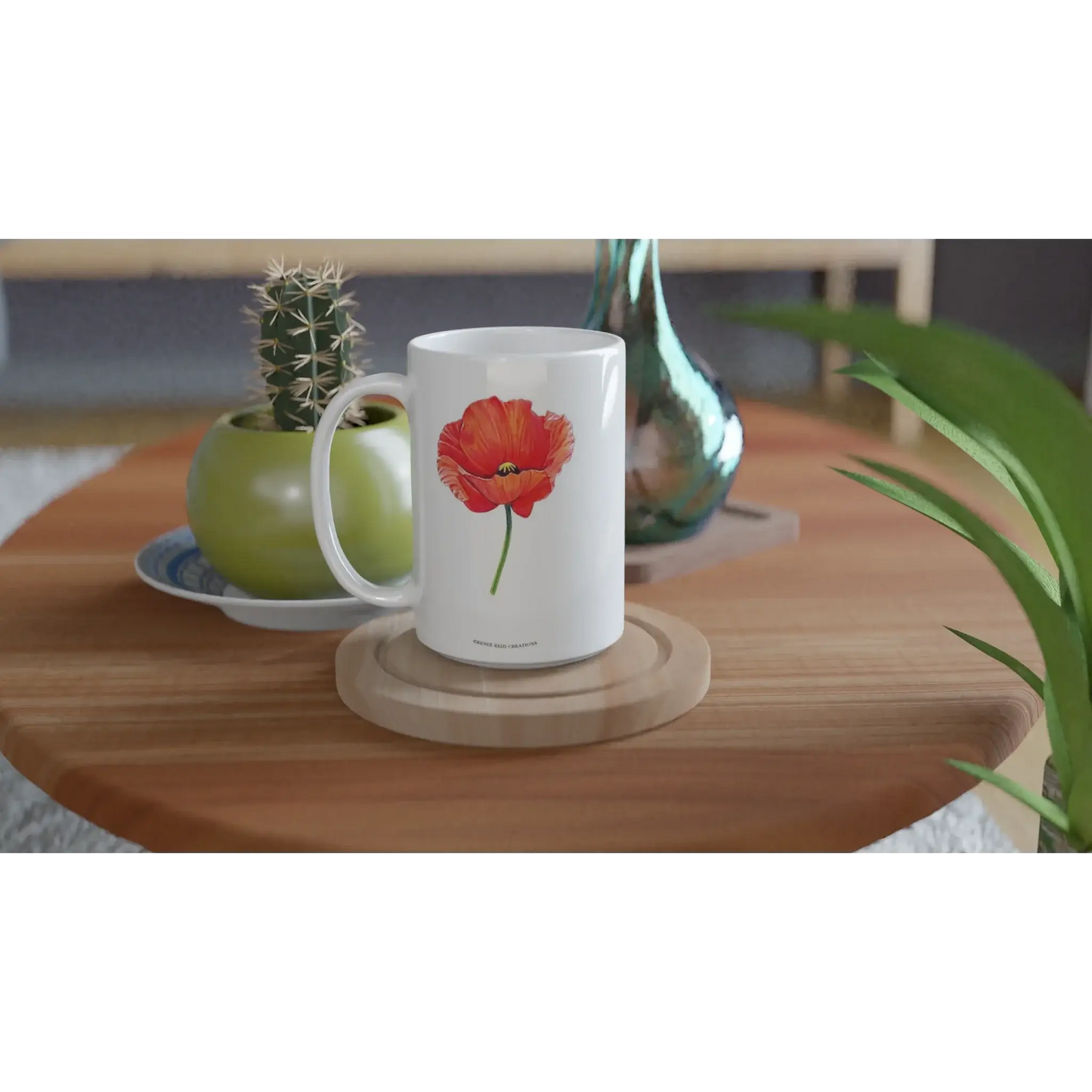 Poppy Flower Mug 15oz displayed on a wooden table with a plant, perfect for adding color to your morning routine.