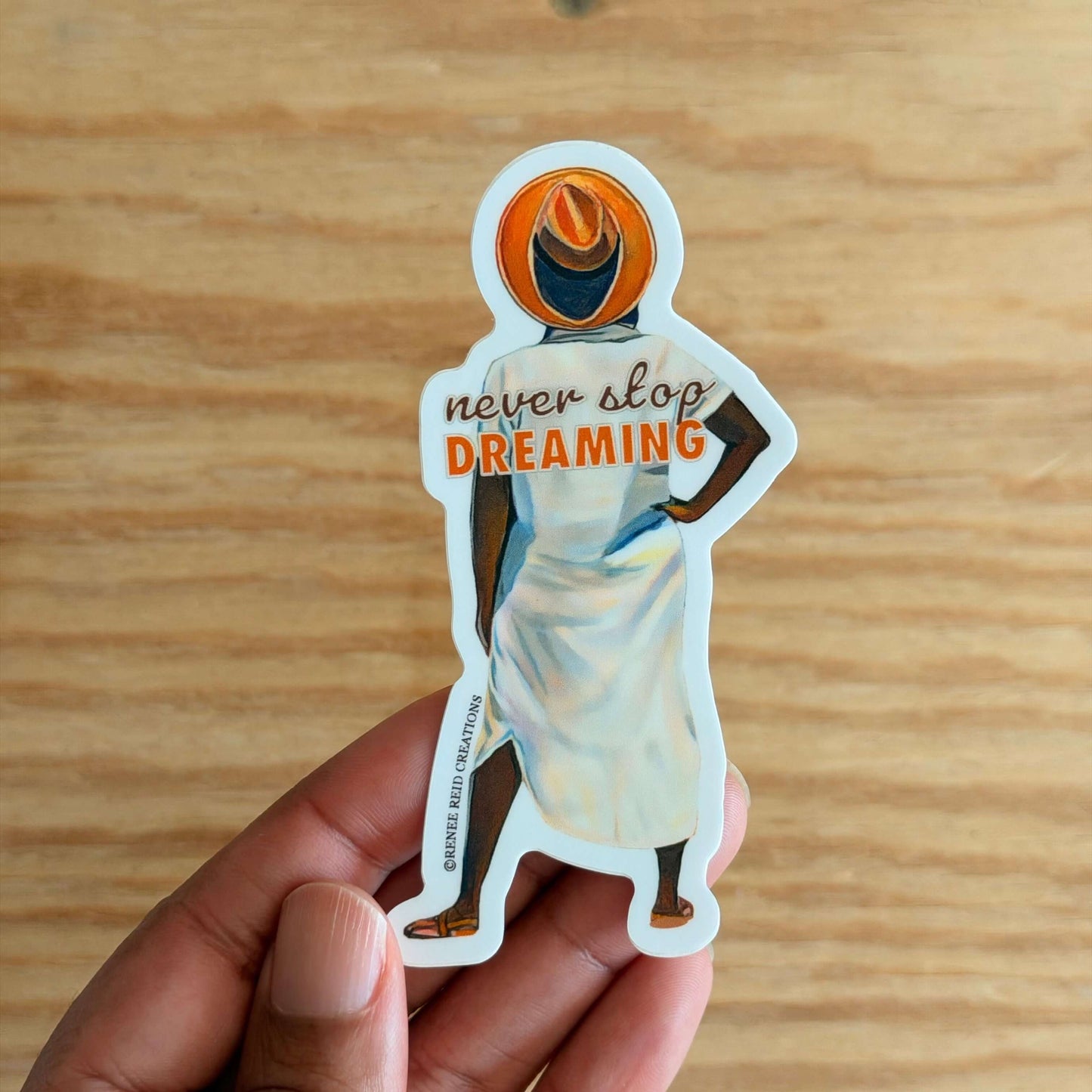 Beyond the Horizon Vinyl Sticker with 'never stop DREAMING' text on a wooden surface.