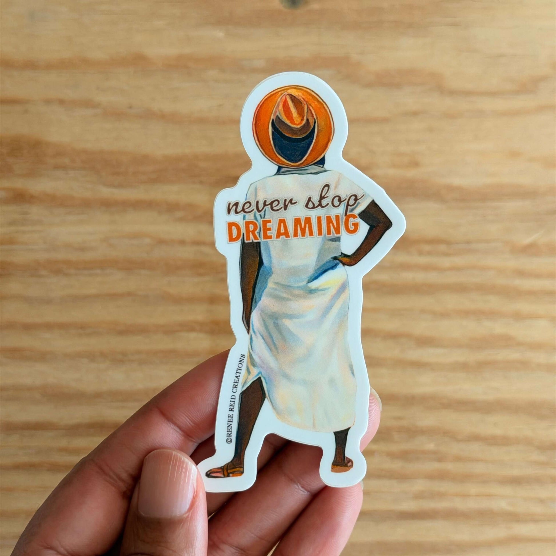 Beyond the Horizon Vinyl Sticker with 'never stop DREAMING' text on a wooden surface.