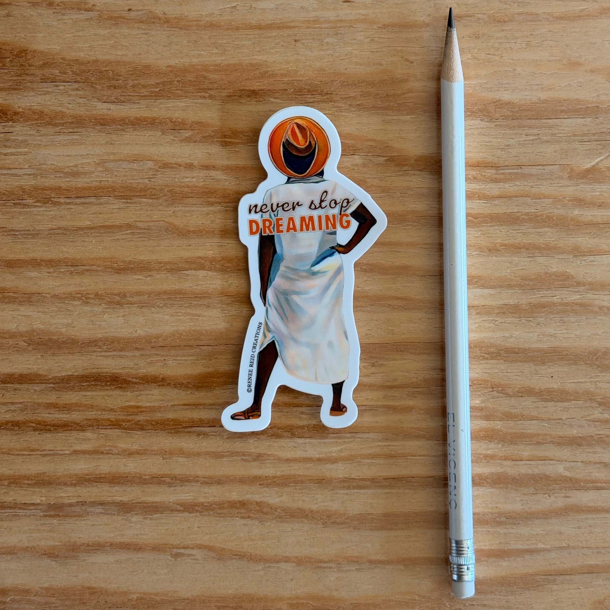 Beyond the Horizon Vinyl Sticker with 'never stop dreaming' text on a wooden surface with a pencil for scale.