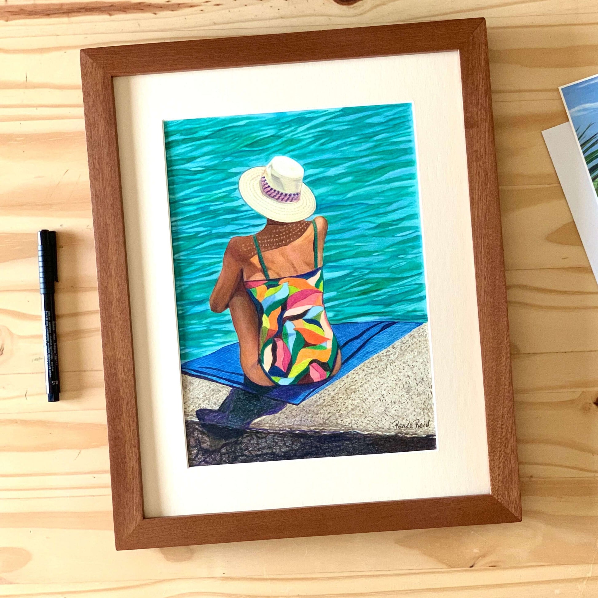 Renee Reid framed original art of a woman in a colorful swimsuit daydream on a seaside landing