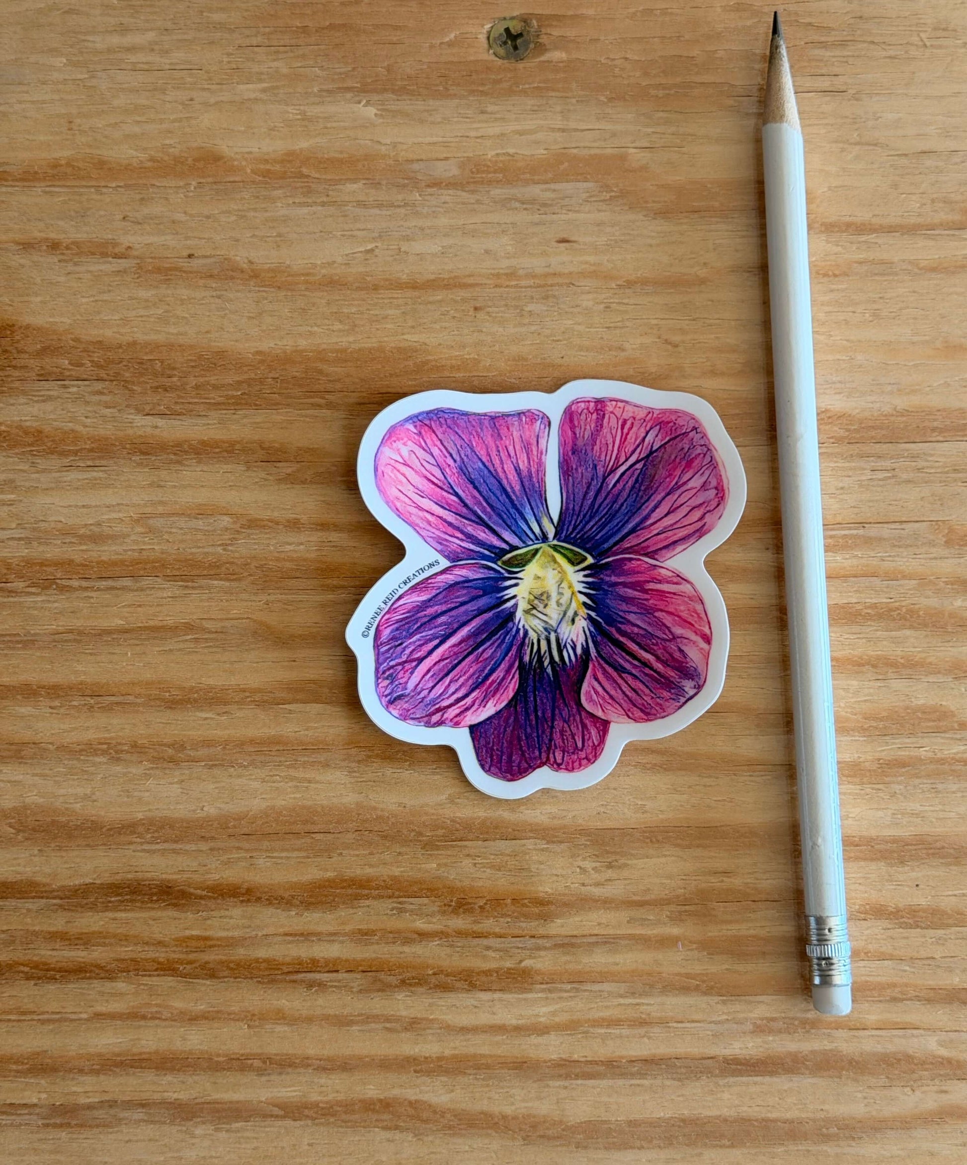 Purple Violet Flower Vinyl Sticker on wooden surface next to a pencil, showcasing vibrant colors and intricate details.