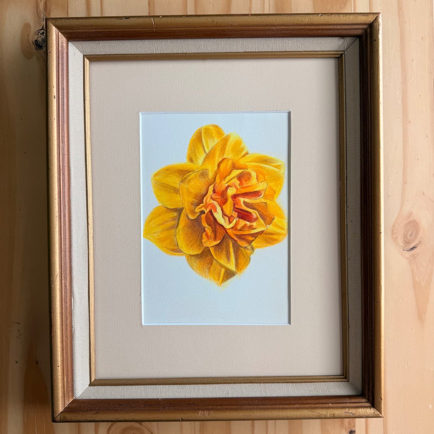 Framed picture of a yellow flower on a wooden wall