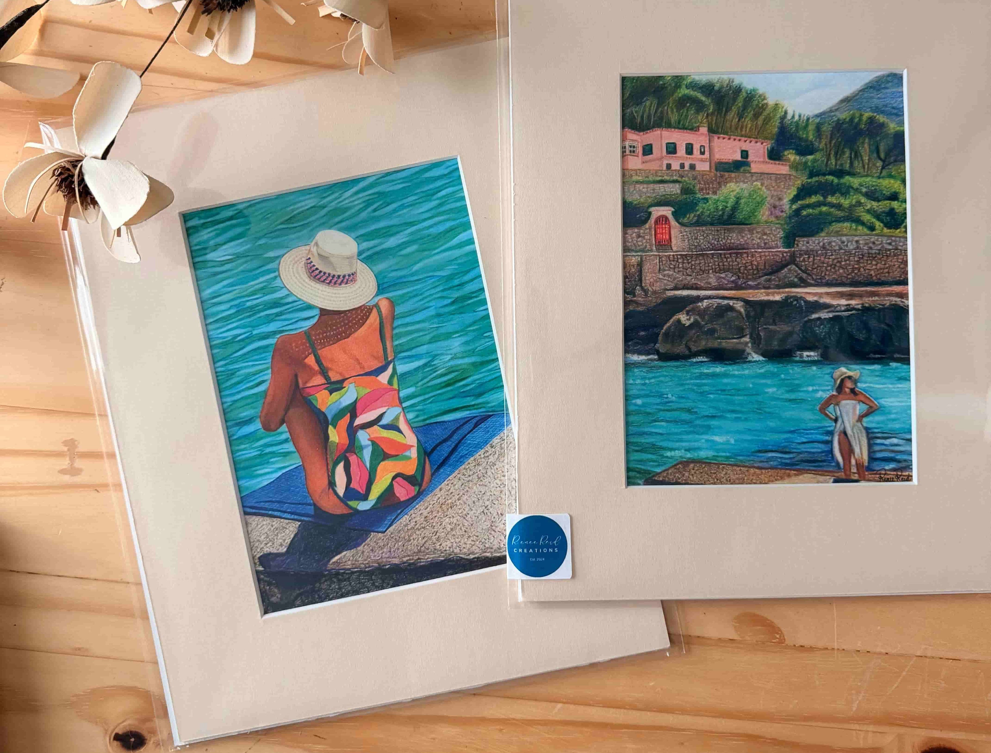 Two framed artworks of a woman by a lake on a wooden surface with a branch and flowers.