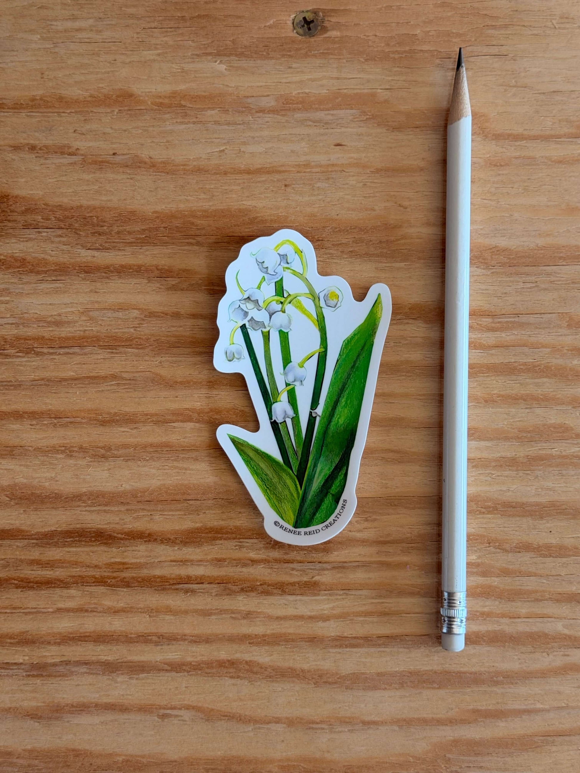 Lily of the Valley Flower Vinyl Sticker next to a pencil on a wooden surface