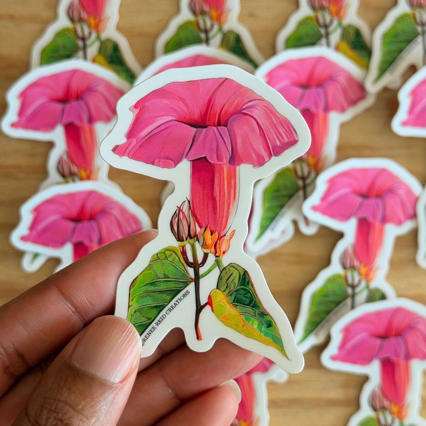 Pink Morning Glory Flower Vinyl Sticker with more stickers in the background on a wooden surface