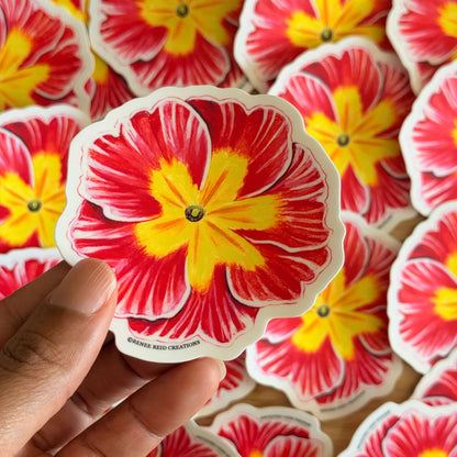 Hand holding a Pink Primrose Flower Vinyl Sticker with more stickers in the background.