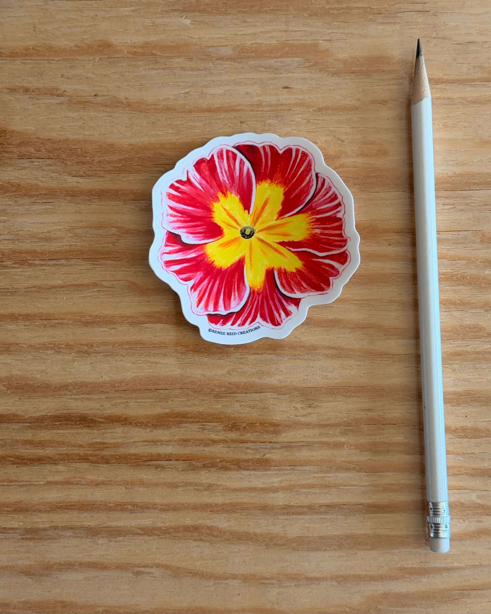 Pink Primrose Flower Vinyl Sticker with red and yellow colors on a wooden surface next to a pencil.