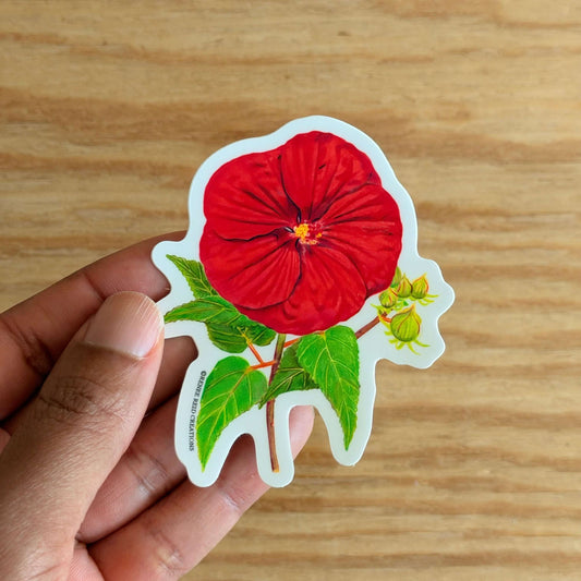Hand holding a Red Hibiscus Flower Sticker on a wooden surface
