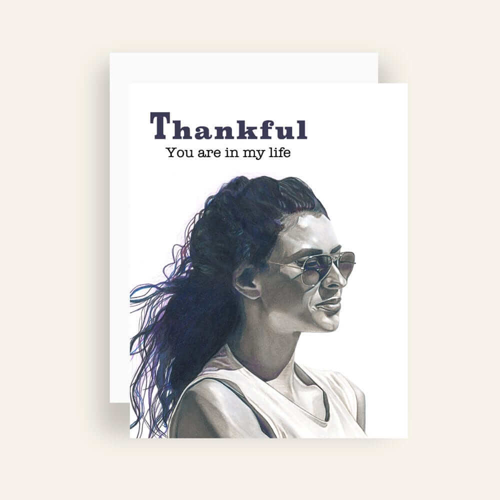 Close up of greeting card with generic text and art of a monochromatic woman with a pensive look wearing sunglasses peering into the distance