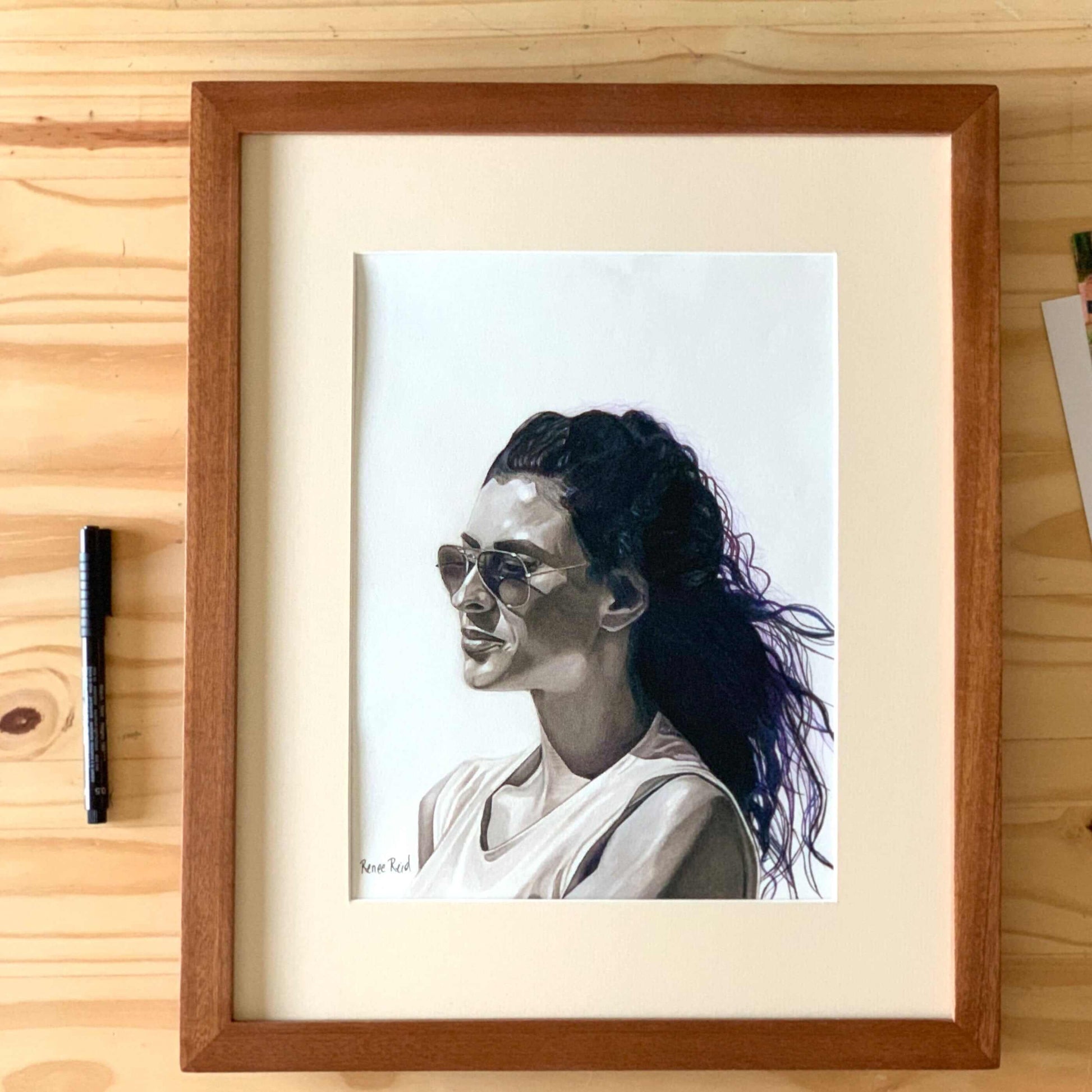 Renee Reid framed original art of a monochromatic woman with a pensive look wearing sunglasses peering into the distance