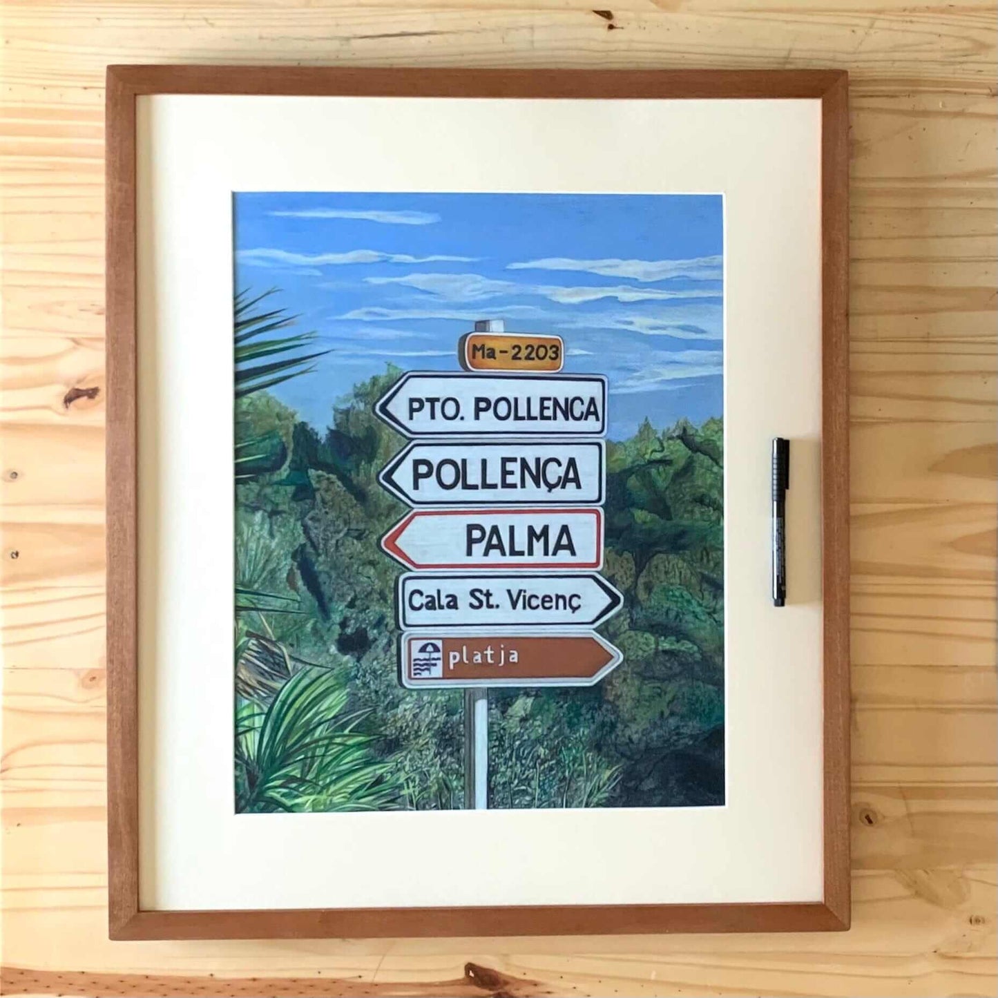 Renee Reid framed original art of a road sign in Mallorca surrounded by green bushes 